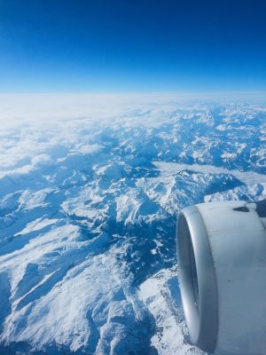 In the air, over the Alps, aerial view of snowy mountains and summits, horizon over land